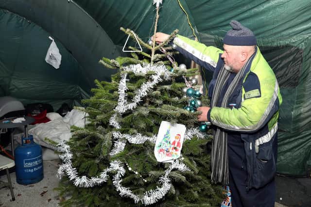 Andrzey decorates the Christmas tree in the tent used as a communal living area