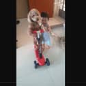 Fluffy dog rides a scooter with help of adorable toddler