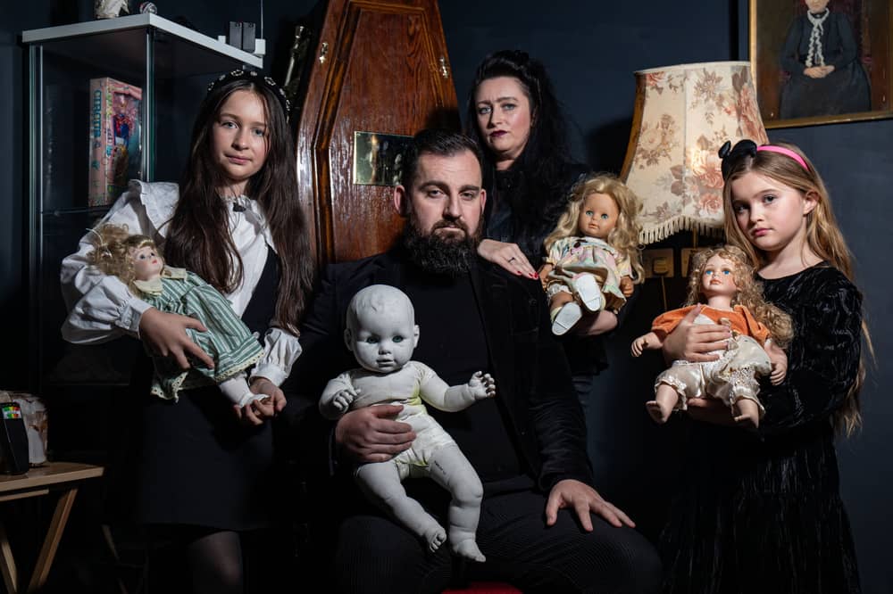 JP Kennedy and Kymmi Jeffery with daughters Snow and Pebble (L-R), known as The Occult Family, holding haunted dolls inside their haunted room.