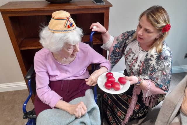 Team member senior day nurse Nico explaining the reason behind their dyeing of eggs to resident