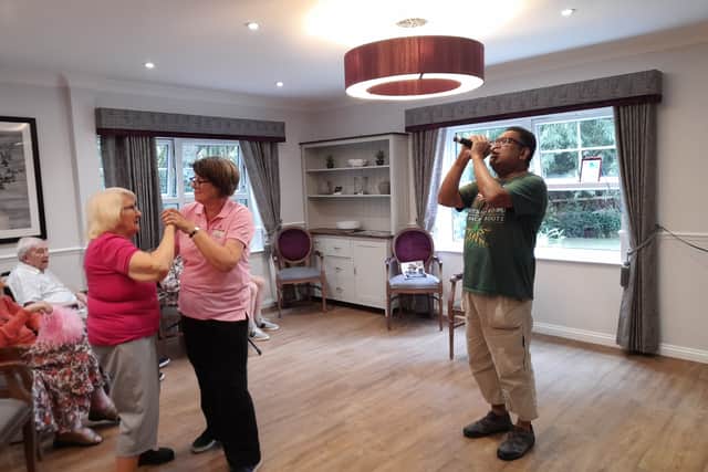Reggae Ray vocalist sings while Resident dancing with activities assistant