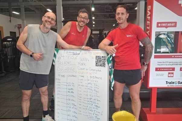 Tracking every kilometre! The team proudly displays their impressive 24-hour progress board clocking in at an incredible 267.59km alongside their donation bucket at the finish line.