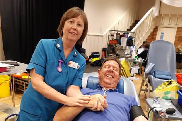 Bill gives blood for the 100th time, pictured with nurse Carol.