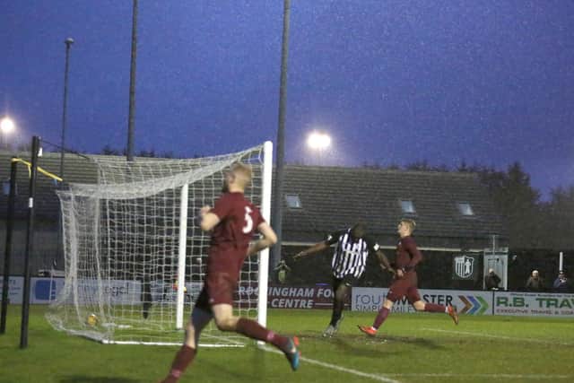 The ball is in the net as Elliot Sandy scores Corby's goal