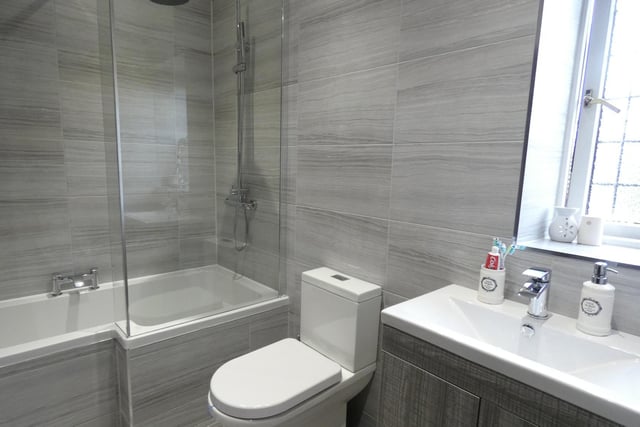 This bathroom within the property has both a bath and shower, with a washbasin vanity unit.