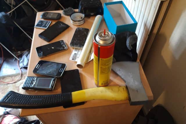 This axe, pictured here with several mobile phones recovered, was one of several weapons found in today's raids.