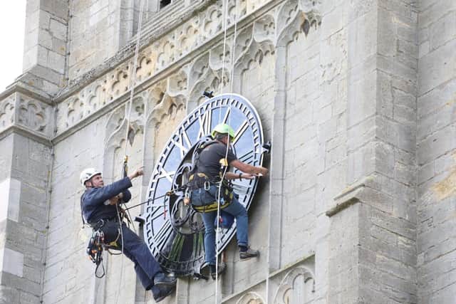 Workers were seen abseiling down the church's 180ft tall tower to carry out the work