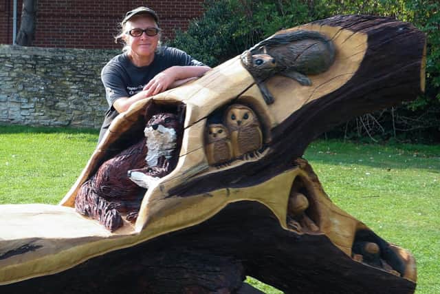 Wood carver Carrie Yuen with some of the creatures she carved into this bench