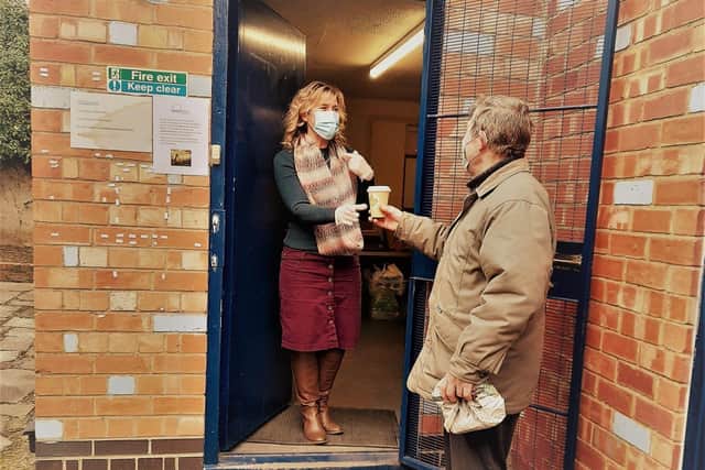 Client and volunteer Steve accepts a hot drink from Carina