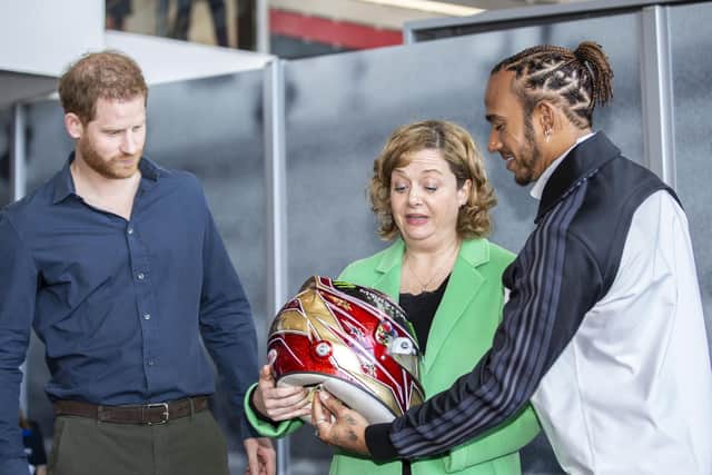 Lewis Hamilton presents his 2019 helmet to The Silverstone Experience chief executive Sally Reynolds alongside Prince Harry