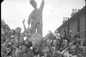 The jubilant crowd show their effigy of Hitler to the camera