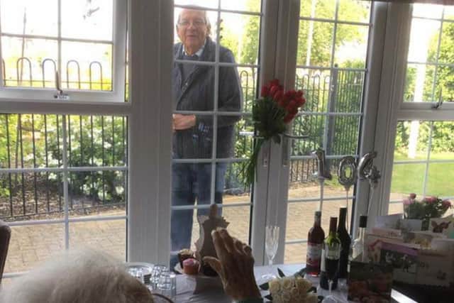 Doreen raising a toast to her 104th birthday through the window with son Clive