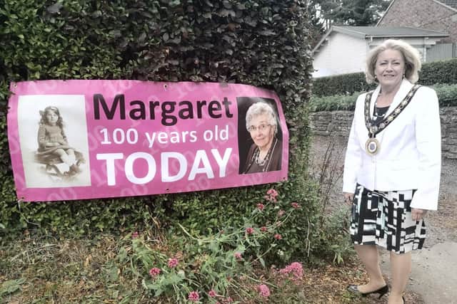 Raunds mayor Cllr Sylvia Hughes by the banner for Margaret Tirebuck's 100th birthday