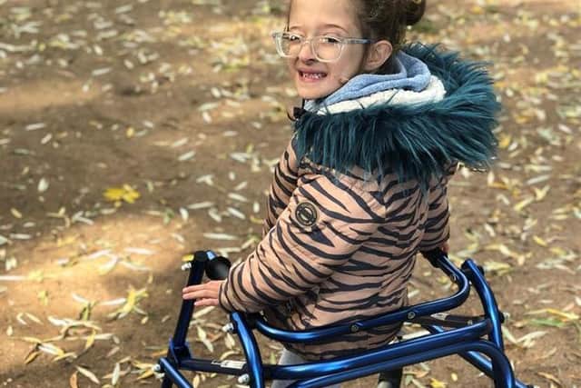 Evie uses a frame to help her walk