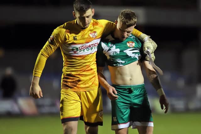 Goalkeeper Jackson Smith puts an arm around a disappointed Jordon Crawford after the forward missed a late chance for the Poppies