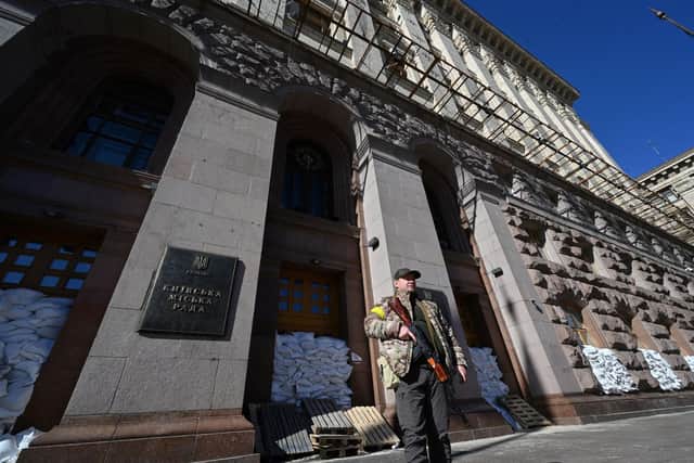 A fighter of the Ukrainian Territorial Defence Forces, the military reserve of the Ukrainian Armed Forces, stands guard in front of the Kyiv City Hall. (Photo by Sergei SUPINSKY / AFP) (Photo by SERGEI SUPINSKY/AFP via Getty Images)