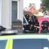 Armed police with their guns pointing through a downstairs window