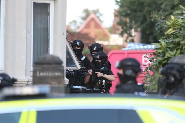 Armed police with their guns pointing through a downstairs window