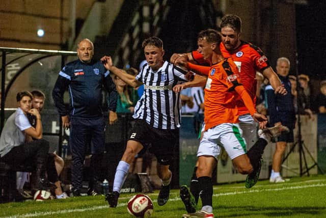 Connor Furey is challenged by two Soham players