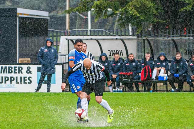 Water splashes up from the pitch as Corby's James Clifton is challenged by a Sutton Coldfield player