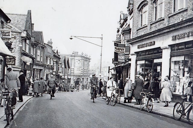 A post-war Rushden High Street with two-way traffic - mostly bikes