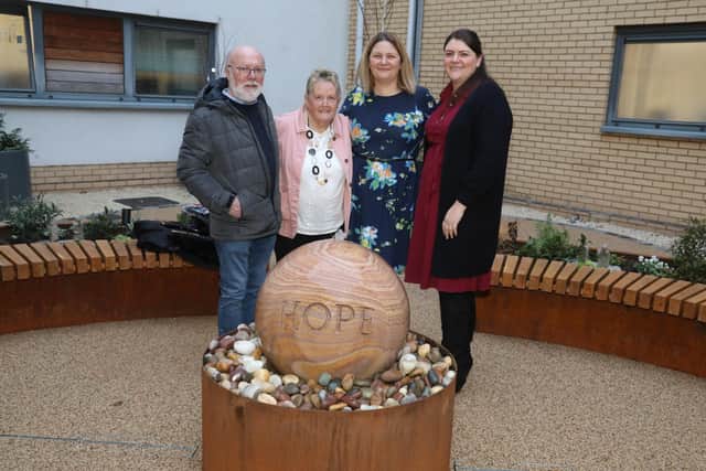 Glennis Hooper in pink jacket, with Marilyn Chapman's family with the water feature at Kettering General Hospital's Treatment Centre/National World