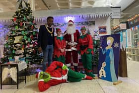 Corby mayor, Cllr Tafadzwa Chikoto (furthest left, standing) along with Santa, his elves, and The Grinch