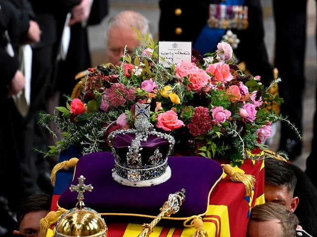 King Charles III walks alongside the coffin carrying Queen Elizabeth II with the Imperial State Crown resting on top as it departs Westminster Abbey during the State Funeral