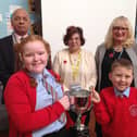 From left to right: Jake Baker, chairman of the Rushden branch of the RBL, Ruth Miller, Poppy Appeal Organiser, and Lynne Baker, Rushden branch secretary pose with students holding the Poppy Cup