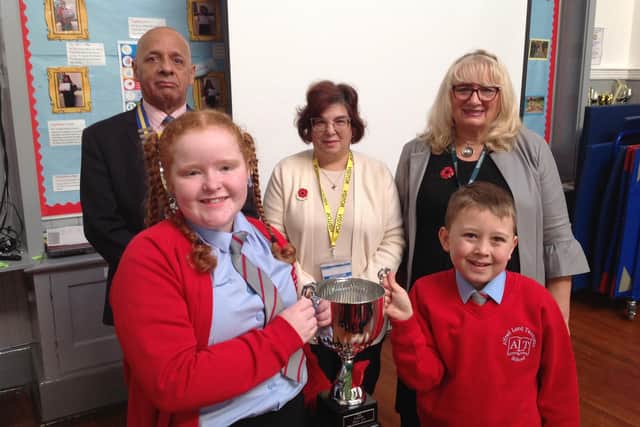 From left to right: Jake Baker, chairman of the Rushden branch of the RBL, Ruth Miller, Poppy Appeal Organiser, and Lynne Baker, Rushden branch secretary pose with students holding the Poppy Cup
