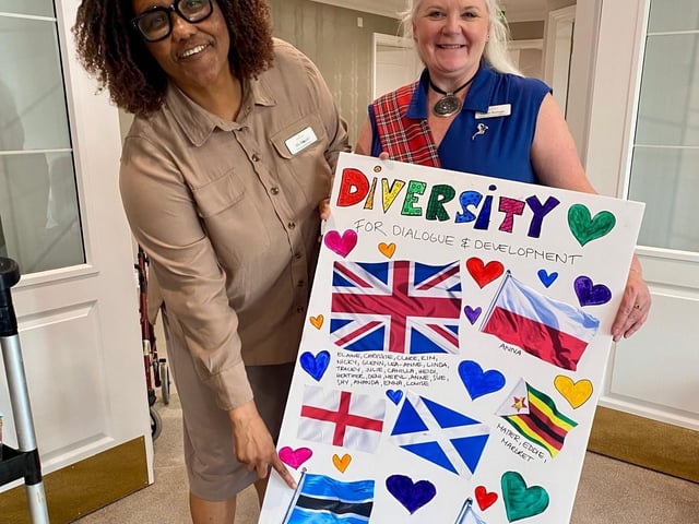 General Manager Mo Masedi and Home Service Advisor Louise from Brampton View Care Home proudly showcase a collection of flags representing various cultures within the home.