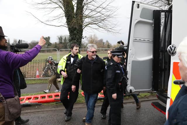 Police escort the first man arrested into a van