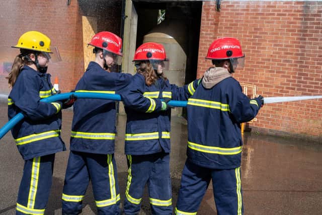 Four young people with a fire hose