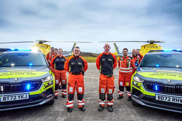 Some of the charity's crew members with their critical care cars and helicopters.
