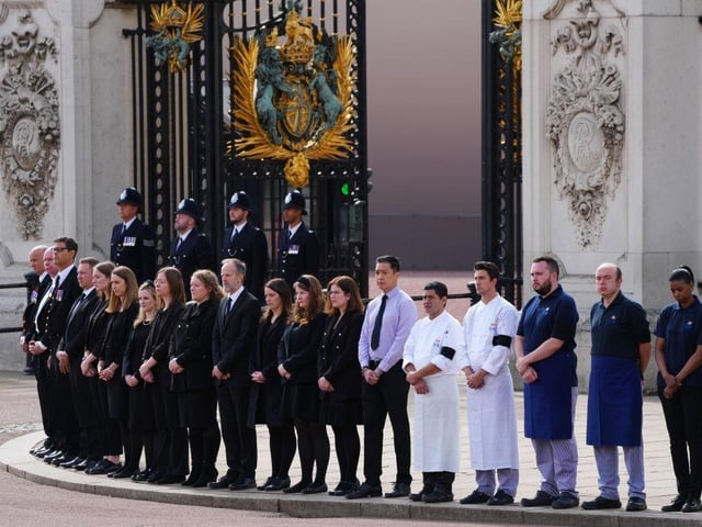 Palace staff pay their respects as the Queen's coffin passes Buckingham Palace for the final time