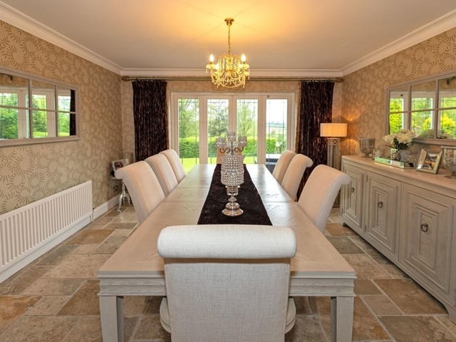 An elegant dining room has French doors leading out to the extensive gardens