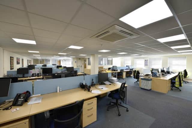 An empty office shows employees' hi-vis jackets still hanging on the back of chairs