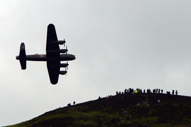 Spectators on a hill look on as a  Lancaster bomber flies over Ladybower reservoir in the Derbyshire Peak District to mark the 65th anniversary of the World War II Dambusters mission on May 16, 2007 in Derwent, England. Ladybower and Derwent reservoirs were used by the RAF's 617 Squadron in 1943 to test Sir Barnes Wallis'  bouncing bomb before their mission to destroy dams in Germany's Ruhr Valley.  (Photo by Christopher Furlong/Getty Images)