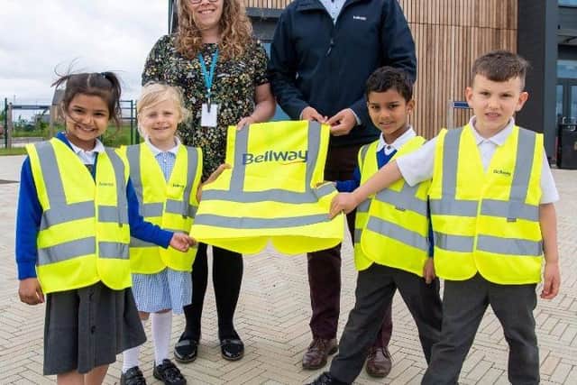 Bellway Sales Manager Andrew Odams, with Head of School Sarah Whitlock and youngsters posing with their hi-vis jackets