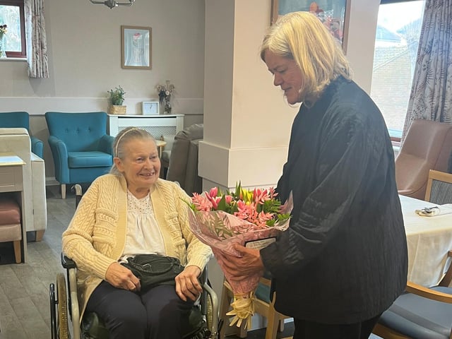 Resident Sandra Collier presenting the Baroness with a bouquet of flowers at Pytchley Court Care Home