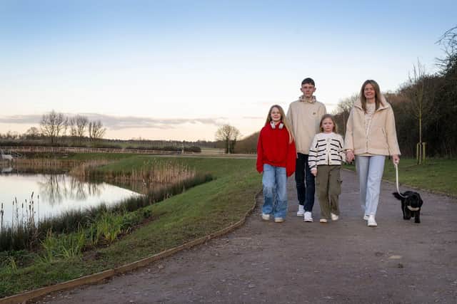 The fogg family  out walking their dog Lyla beside the lake at Davidsons Homes’ Kirby Woodlands development in Northamptonshire