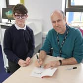 Josh Lavey signing a book for a Year 4 pupil