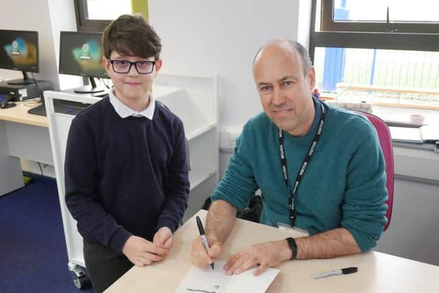 Josh Lavey signing a book for a Year 4 pupil