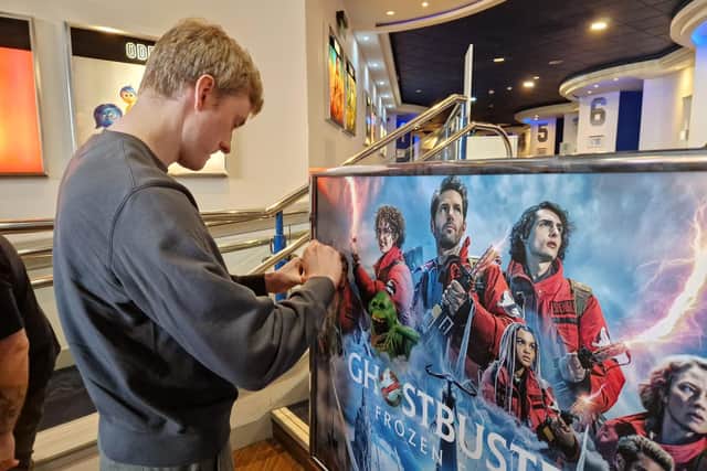 James Acaster star of Ghostbusters:Frozen Empire signs the poster on display at the Odeon in Kettering/National World