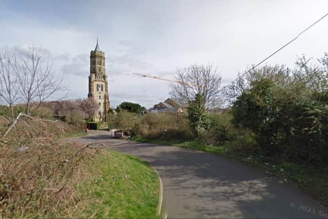 The current appeal site with the tower of St Peter's Church in the background. The flats are proposed to be built in the undeveloped scrubland to the right of the road. (Credit: Google)