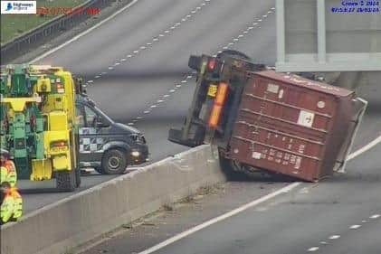 The lorry overturned on the A14 rests on the central reservation/ National Highways