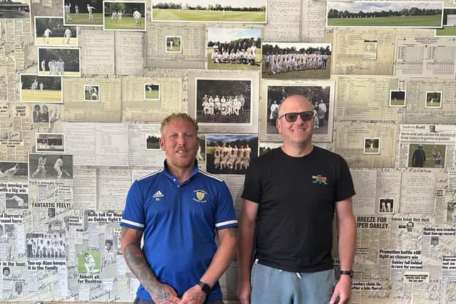 Great Oakley Cricket Club chair, Ash York (right), and nephew Alan York (left), who is the club groundsman, in front of the club's newspaper clippings wall