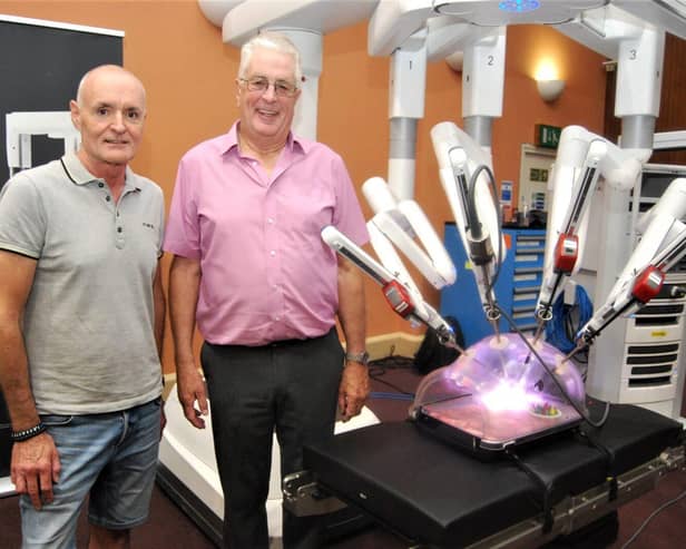 Patients Ian Dowell and Ross Thompson with the robot.