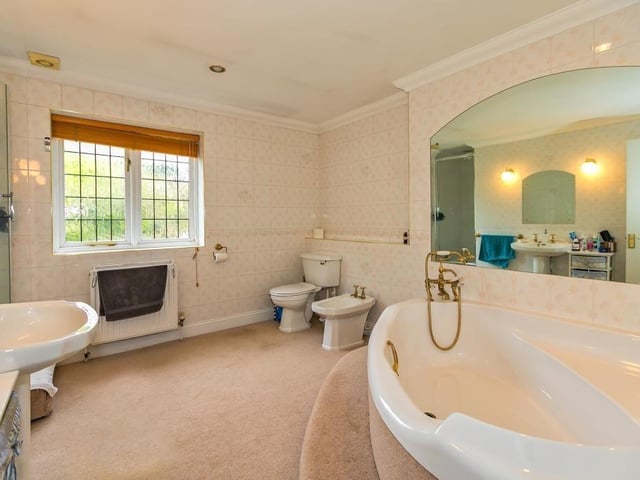 A large family bathroom comes with a corner bath with steps and a seat