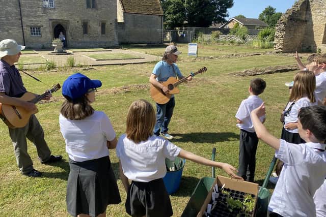 Year 5 pupils of Higham Ferrers Junior School plant a mini meadow accompanied by
musicians Robin Bain and Michael Parker